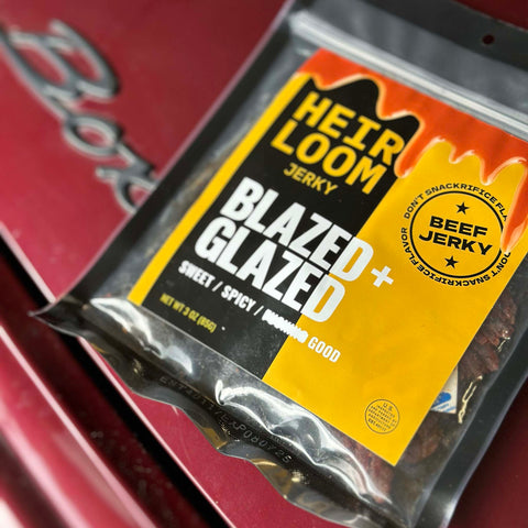 A bag of Blazed & Glazed beef jerky by Heirloom Jerky that has been placed on the hood of a car.