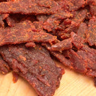 A closeup photo of Honey Badger beef jerky that shows the large pieces of jerky coated in a marinade. 